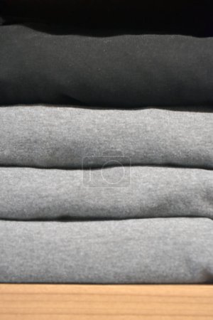 Photo for Stack of gray and black clothes on a shelf in clothing store. Clothing store fashion. - Royalty Free Image