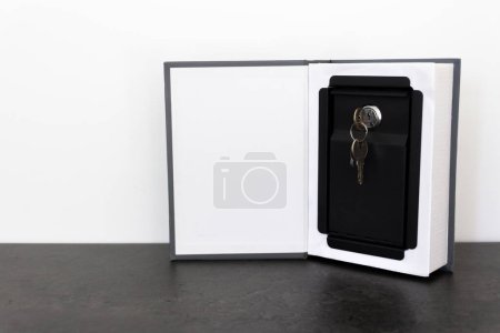 Foto de Una caja fuerte inteligente con llaves en la cerradura es un lugar discreto para guardar sus ahorros. La caja fuerte está disfrazada de libro.. - Imagen libre de derechos