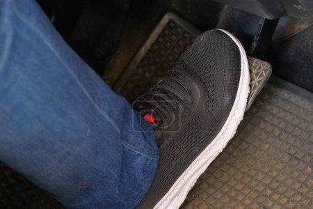 Photo for A foot stepping on the brake ready to start an automatic car. Close up right foot with black shoe step on the car brake to reduce speed. A man pressing brake pedal by foot to slow down the car. - Royalty Free Image