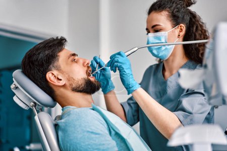 Zahnmedizin, Medizin. Eine Zahnärztin in Maske behandelt die Zähne einer Patientin.