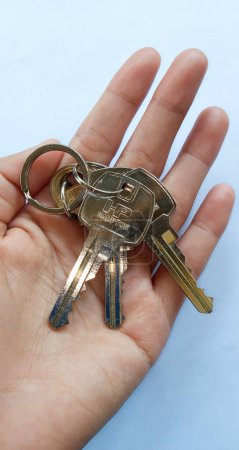 Photo for Soppeng, Indonesia-December 2022: Women hand's holding the house keys set on white background. - Royalty Free Image