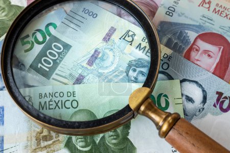 Mexican money, top denominations, magnifying glass, finance concept