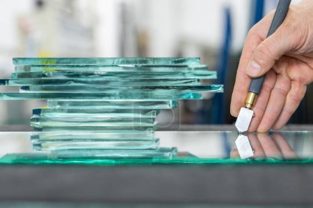 Gros plan de la main d'un vitrier lorsqu'il coupe du verre dans une usine de verre, Gros plan, Pièces de verre épais