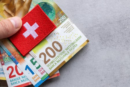 Schweizer Geld und Nationalwappen in der Hand, grauer Hintergrund, Kopierraum, Flay, Finanzhintergrund