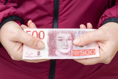 A woman holds 500 Swedish kronor in her hands, Financial concept, Household budget, rising inflation