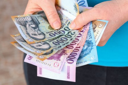 Ungarisches Forint-Geld, Frau umklammert eine Handvoll Banknoten, Große Stückelungen, Inflation und Finanzlage in Ungarn