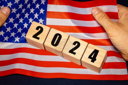 2024, USA, amerikanische Flagge in Händen und Datumsblöcken, Konzept, Wichtige Ereignisse für die Amerikaner im neuen Jahr, Wahlen, Wirtschaft, soziale Aktivitäten, Zentralbank, US-Außenpolitik, Nahaufnahme