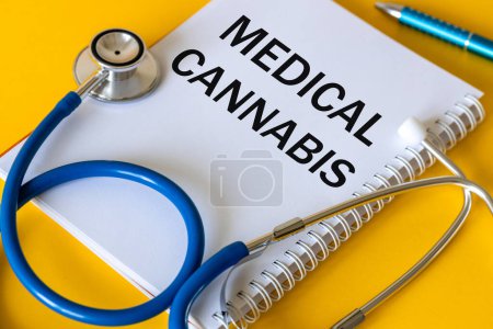 Foto de Estetoscopio médico, cuaderno blanco con la inscripción Cannabis medicinal, hermoso fondo amarillo, El uso de cannabis y marihuana en la medicina - Imagen libre de derechos
