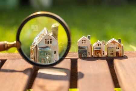 Beautiful miniatures of ceramic houses, magnifying glass, concept, real estate, buying a house, building a house, mortgage, housing related