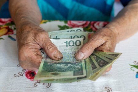 Eine alte Frau hält 100 polnische Zloty-Scheine in der Hand, polnisches Geld, Konzept, Rente, Taschengeld, Altenhilfe.
