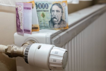 Téléchargez les photos : Hongrie, coût de l'énergie dans les ménages, appartements de chauffage, période d'hiver, coûts de l'électricité et du gaz, argent hongrois sur le radiateur - en image libre de droit