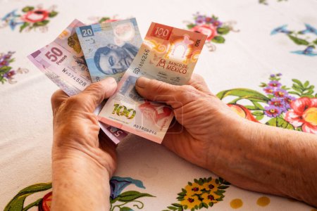Mexique argent, Eldelry femme tient plusieurs billets de banque en pesos mexicains dans sa main, Problèmes financiers des retraités, faibles retraites, prix élevés