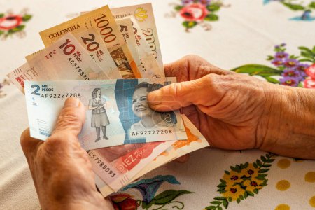Foto de Peso colombiano, pensionista con varios billetes en la mano, problemas financieros de personas mayores, inflación y pobreza en Colombi - Imagen libre de derechos