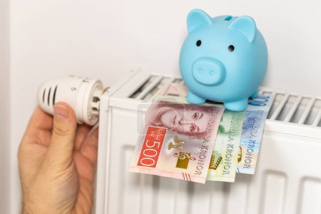 Téléchargez les photos : Les coûts de chauffage des appartements en hiver en Suède, l'énergie et le concept économique, main dévisser le radiateur, tirelire et la couronne suédoise - en image libre de droit