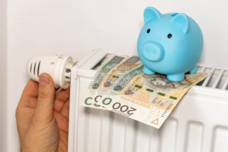 Téléchargez les photos : Les coûts de chauffage des appartements en hiver en Pologne, l'énergie et le concept économique, main dévisser le radiateur, tirelire et argent polonais - en image libre de droit
