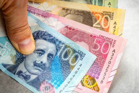 Téléchargez les photos : Argent péruvien, Billets de banque péruviens au sel tenus en main, Concept financier, fond gris. espace de copie - en image libre de droit