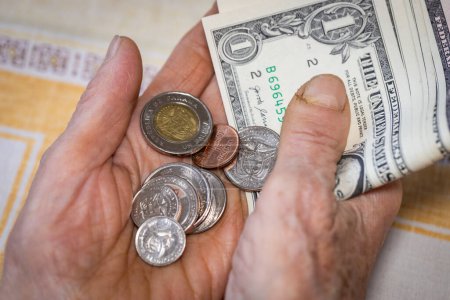 Panama, Hands of an old person who is holding a handful of Balboa coins and several one dollar bills, Economic concept, Financial problems of retirees and elderly people in Panama