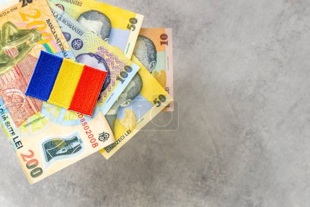 Téléchargez les photos : Roumanie argent, fond gris, espace de copie, divers billets de banque en leu roumain et beau drapeau de pays brodé - en image libre de droit