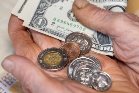 Panamá, Manos de un anciano que sostiene un puñado de monedas de Balboa y varios billetes de un dólar, Concepto económico, Problemas financieros de jubilados y ancianos en Panamá