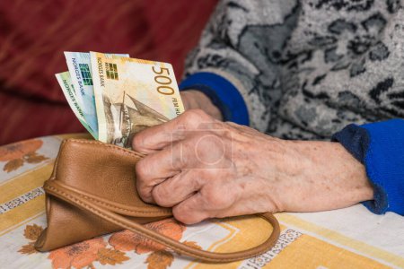 a small amount of Norwegian kroner in the hands of a pensioner, Financial concept, Problems of older people in Norway