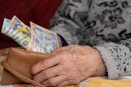 Eine alte Frau zieht einen kleinen Betrag rumänischer Lei aus ihrem Portemonnaie, Finanzkonzept, steigende Lebenshaltungskosten und Schwierigkeiten der Rentner in Rumänien