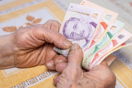 Las manos de una anciana tienen varios dólares de Singapur en sus manos, concepto económico, presupuestos de los pensionistas en Singapur, aumento del costo de vida y gastos