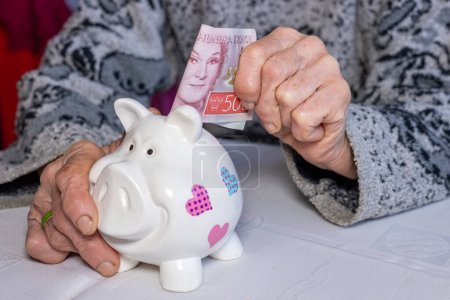 Schweden Geld, Rentner legt 500 Schwedische Kronen in ein Sparschwein, Finanzkonzept, Sparen und finanzielle Sicherheit älterer Menschen