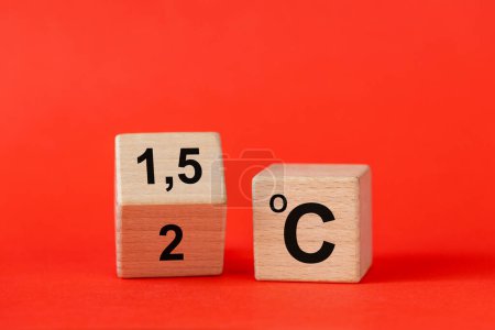 Symbol for limiting global warming. A rotating wooden cube with the symbol "2 C" turning into "1.5 C" Concept. Global warming reduction icon or vice versa. climate change, red background. copy space