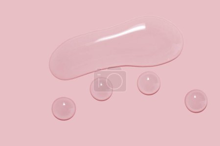 Téléchargez les photos : Large drops of cosmetic serum, liquid, water, gel on a pink background - en image libre de droit