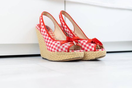 Photo for Red White open shoes with a high wedge heel in front of a closet. High quality photo - Royalty Free Image