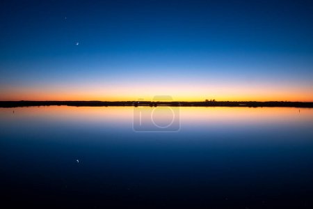 Foto de Puesta de sol en las marismas de Sanlúcar de Barrameda, con el Parque Nacional Donana al fondo. - Imagen libre de derechos