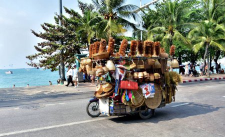 Téléchargez les photos : Thaïlande - Février 2018 : Moto chargée roule le long de la route sur le bord de la mer en Thaïlande - en image libre de droit