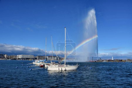 Photo for Geneva, Switzerland - February 4, 2023: Beautiful view of water jet fountain with rainbow and boats at the harbor of Geneva, lake Leman, Switzerland. - Royalty Free Image