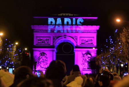 Téléchargez les photos : Paris, France - 1er janvier 2023 : Des foules se rassemblent sur les Champs-Élysées à Paris pour célébrer la transition vers 2023 avec des feux d'artifice sur l'Arc de Triomphe) - en image libre de droit