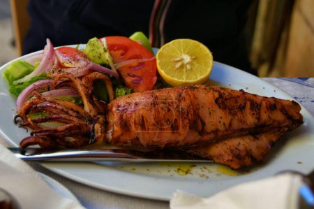 Foto de Primer plano de deliciosos calamares y verduras a la parrilla, ensalada griega, recién hecha en la isla de Egina, Grecia. - Imagen libre de derechos