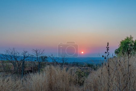Photo for A sunset over a mountain. The sun's rays shining on the peaks create a range of colors, from warm oranges and yellows to cool purples and blues. - Royalty Free Image
