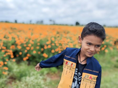 Téléchargez les photos : Portrait de garçon adorable jouant dans un champ de ferme, enfant de 6-7 ans portant des vêtements chauds debout avec un drôle de visage à l'extérieur en automne, enfant explore la nature à la campagne - en image libre de droit