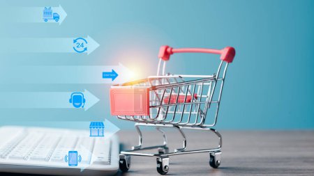 Foto de Shopping cart and keyboard on table,Ecommerce concept and online selling website,Retail business with cyberspace technology used to communicate between store owner and customer. - Imagen libre de derechos