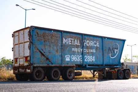 Foto de Una gran papelera de reciclaje de metales azul y bien gastada espera una nueva carga de chatarra encima de un remolque de camión de 18 ruedas. - Imagen libre de derechos