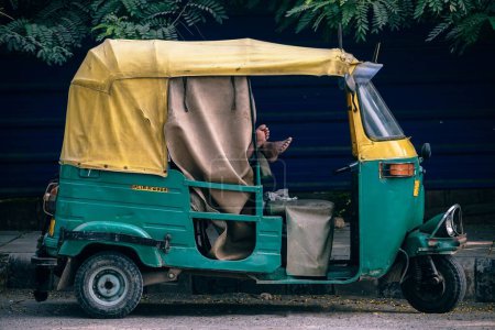 Téléchargez les photos : Asiatique indien jaune et vert autorickshaw de couleur debout sur la rue latérale. Fond flou. - en image libre de droit