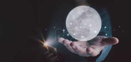 Téléchargez les photos : L'homme montre concept de technologie future et réseau de connexion Internet sans fil avec téléphone mobile. Montrant une photo de la lune flottant dans sa main. - en image libre de droit