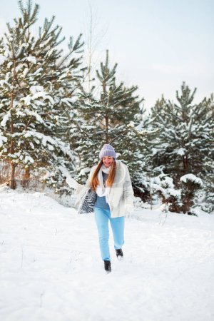 Foto de A walk in a winter forest in Poland. Warm dress. Pine trees in the snow. Winter shoes. A lot of snow is falling from the trees - Imagen libre de derechos
