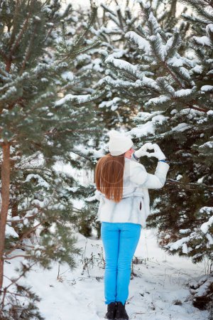 Foto de A snowy coniferous forest in January in Ukraine. The girl walks and enjoys the beautiful winter nature - Imagen libre de derechos