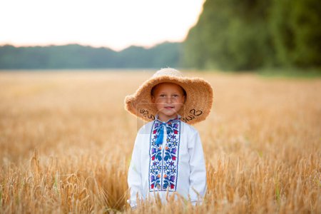 Foto de Vinnytsia, Ukraine. July 15, 2022. A boy in a hat and a white embroidered shirt in a field - Imagen libre de derechos
