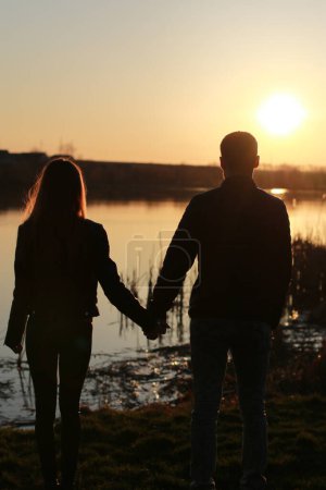 Foto de Husband and wife holding hands at sunset. Silhouettes of a couple in love - Imagen libre de derechos