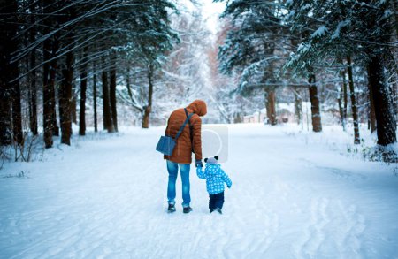 Foto de Two boys are walking in a snowy park and are looking for Santa - Imagen libre de derechos