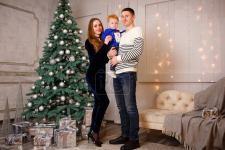 Foto de Ukrainian family is standing near the Christmas tree and waiting for Christmas and many gifts. Copy space - Imagen libre de derechos