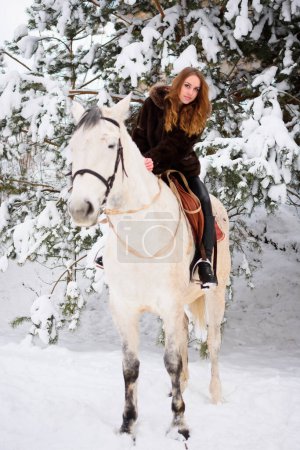 Téléchargez les photos : Winter coniferous forest with snow. Young girl with long hair on a horse. Christmas vacation - en image libre de droit