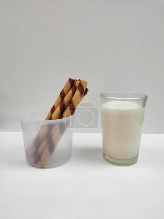 Varilla de oblea de chocolate con vaso de leche fresca aislada sobre fondo blanco