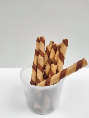 Crispy chocolate cream-filled rolled wafer sticks in a transparent container 